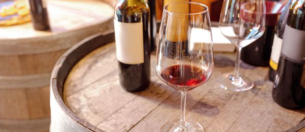Rotwein, Weingläser und Flaschen auf Fass